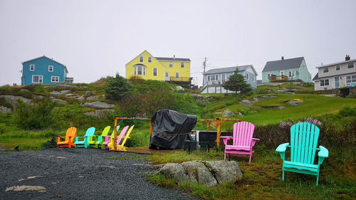 Empty chairs against buildings in city against clear sky