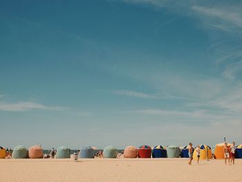 Rear view of people on beach against sky