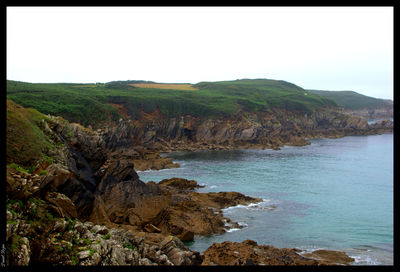 Scenic view of sea and mountains against clear sky