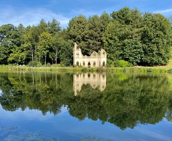 Reflection of trees and house in lake against sky