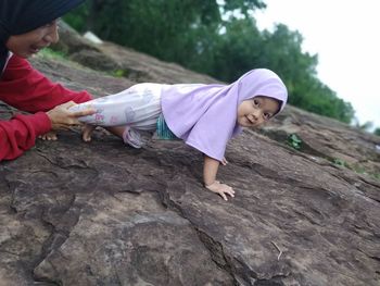 Rear view of mother and daughter on rock