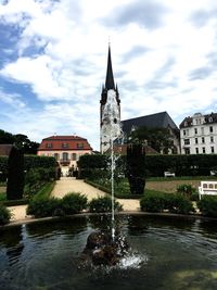 Fountain in city against sky