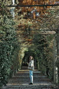 Portrait of woman standing on footpath by building