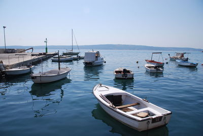 Sailboats moored on sea against clear sky