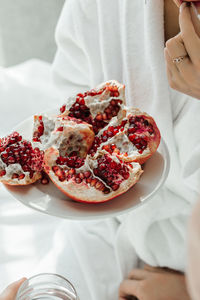 Couple in love in white bathrobes eating ripe red pomegranate