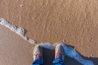 Low section of man standing on sand