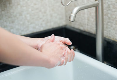 Midsection of woman with arms raised in bathroom