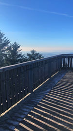 Railing by trees against blue sky