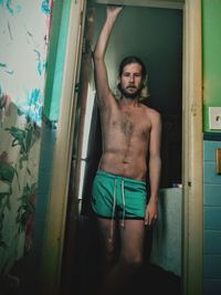 Portrait of shirtless man standing on doorway at home