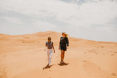 Full length of friends walking on desert