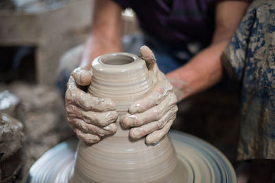 Midsection of woman making clay pot in workshop