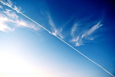 Low angle view of vapor trails in blue sky