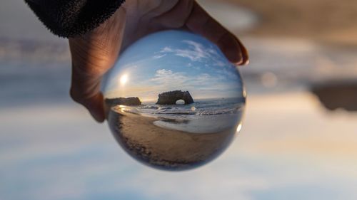 Close-up of hand holding crystal ball at beach