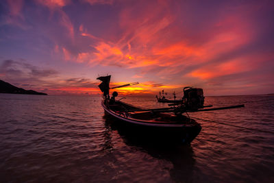 Silhouette boat in sea against orange sky