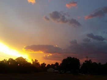 Silhouette trees against dramatic sky during sunset