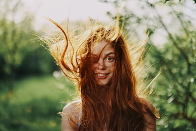 Portrait of young woman standing against plants