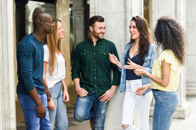 Happy friends talking while standing in city