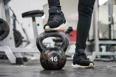 Low section of person standing on kettlebell at gym