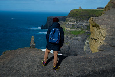 Rear view of man standing on rock by sea