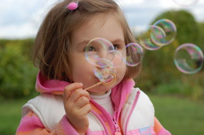 Close-up of girl blowing bubbles on field