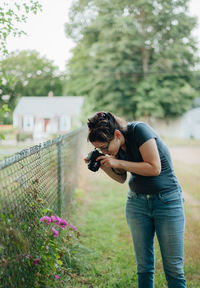 Side view of woman standing on fence against plants