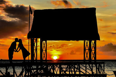 Silhouette man by sea against sky during sunset