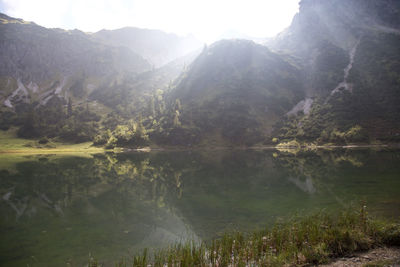 Scenic view of lake by mountains against sky