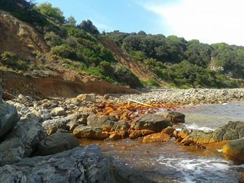 Scenic view of rocks by river against sky