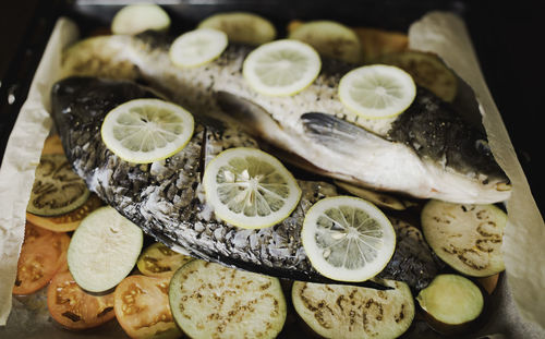 Fish with lemon and vegetables, tomatoes, eggplant on waxed paper, prepared for baking