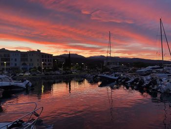 Sailboats moored at harbor during sunset