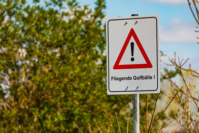 A caution warning sign with the german text caution flying golf balls - fliegende golfbälle