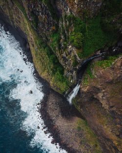 Waterfall falling into the ocean from a high cliff