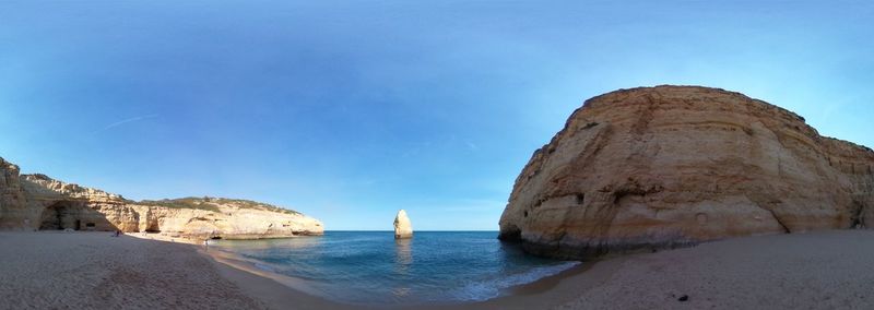 Panoramic view of sea and rock formations against blue sky