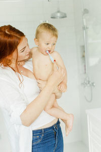 Mother with baby cleaning teeth in bathroom