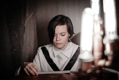 Young man looking down while sitting on table