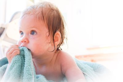 Cute baby boy biting towel at home