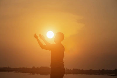 Silhouette man standing by sun during sunset