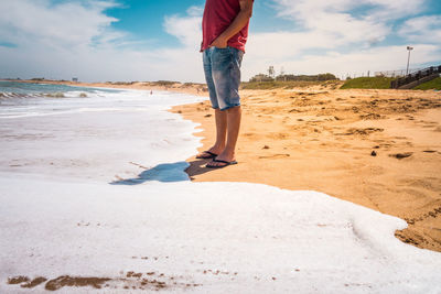 Low section of man standing on beach