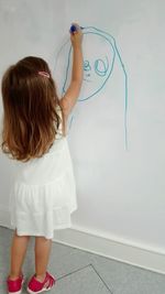 Rear view of girl standing against wall