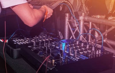 Club dj holding laptop over sound mixer at nightclub