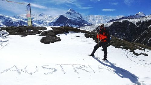 Male hiker standing on snowcapped mountain against sky