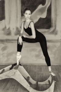 Cute charming young ballerina in a warm-up bodysuit posing in a loft