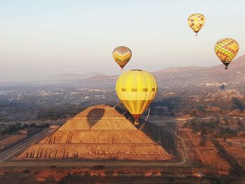 Hot air balloons flying over ancient pyramid