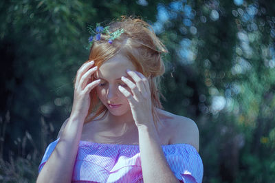 Close-up of beautiful young woman suffering from headache in forest