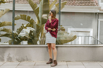 Full length of fashionable young woman standing on footpath in city