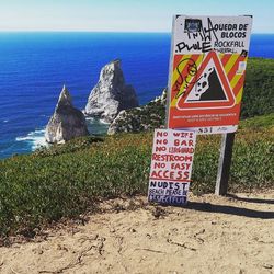 Information sign on rock by sea against sky