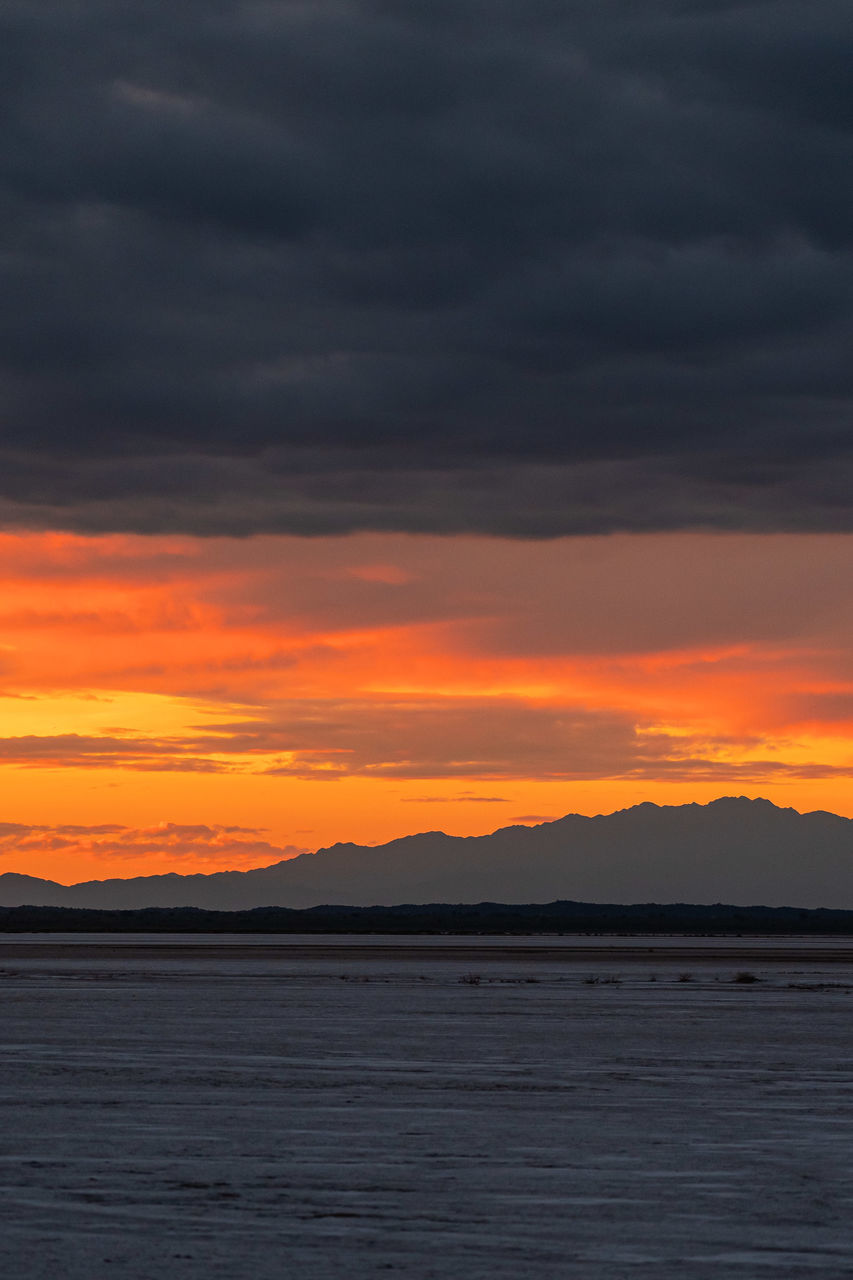 sky, cloud, beauty in nature, sunset, scenics - nature, water, sea, tranquility, nature, dramatic sky, tranquil scene, orange color, mountain, ocean, horizon, no people, environment, coast, idyllic, afterglow, land, outdoors, landscape, red sky at morning, non-urban scene, silhouette, beach, mountain range, shore, moody sky