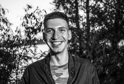 Portrait of smiling young man standing by trees