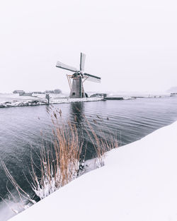 Crane on snow covered land against clear sky