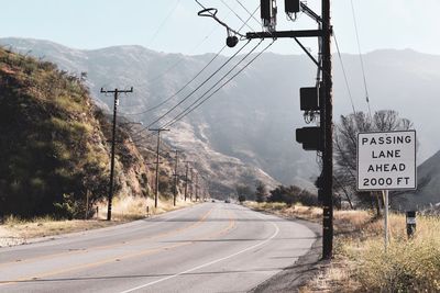 Road sign by mountains against sky